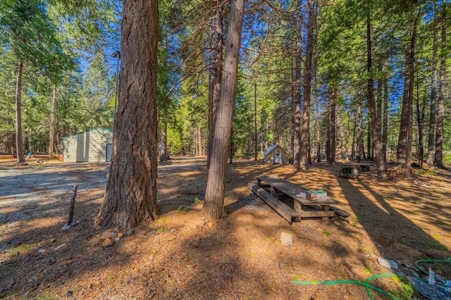 view of yard with an outbuilding and a view of trees