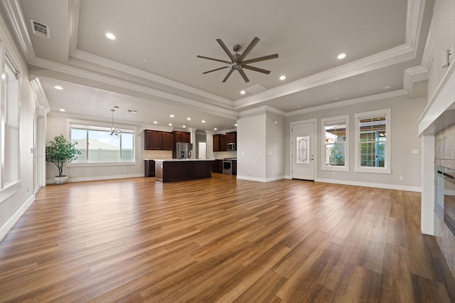 4461 Risstay Way, Shasta Lake, CA 96019 - unfurnished living room featuring wood finished floors, visible vents, a tray ceiling, a tiled fireplace, and ceiling fan with notable chandelier
