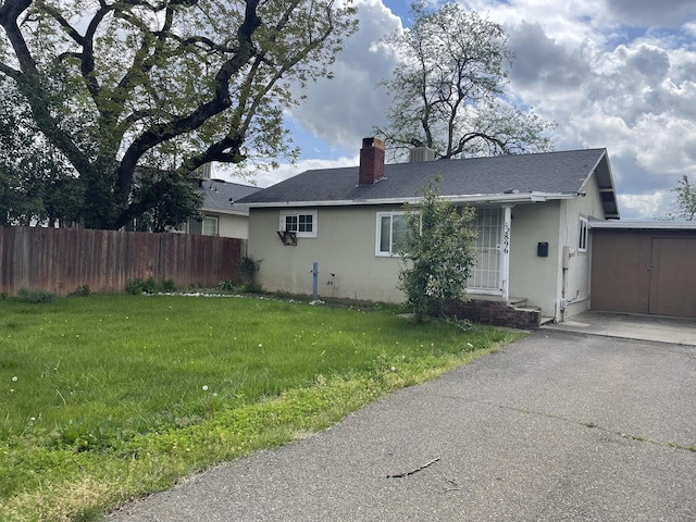 view of home's exterior with a chimney, fence, a lawn, and stucco siding
