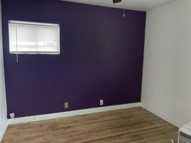 unfurnished room with baseboards, wood finished floors, and ceiling fan