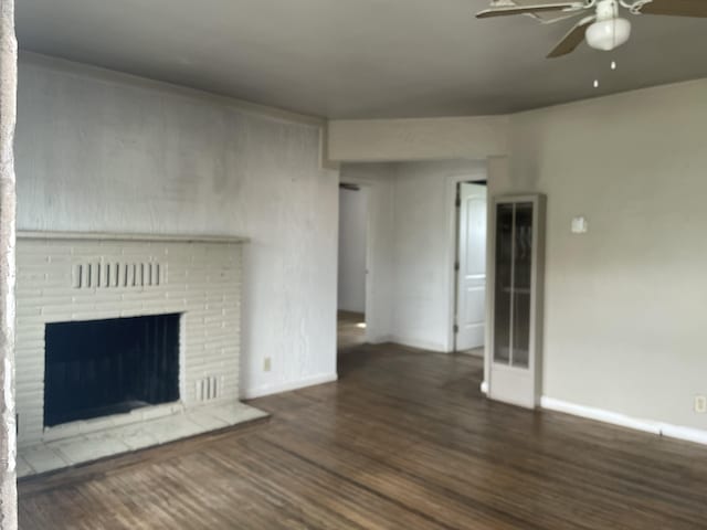 unfurnished living room with baseboards, a ceiling fan, wood finished floors, and a fireplace