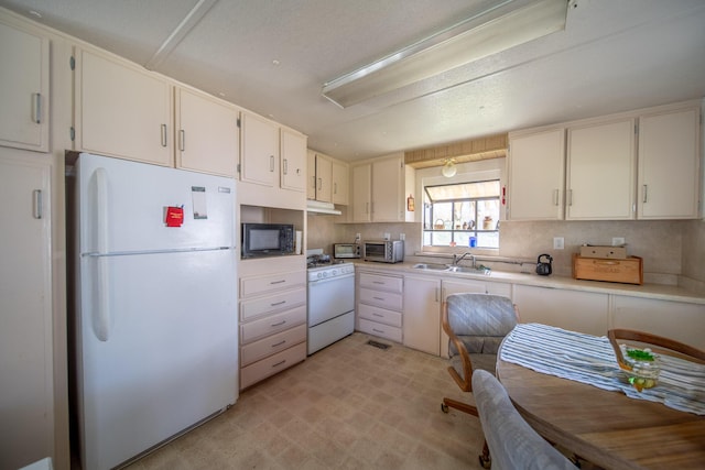 20292 Old Alturas Rd, Redding, CA 96003 - kitchen featuring white appliances, under cabinet range hood, light countertops, a sink, and decorative backsplash