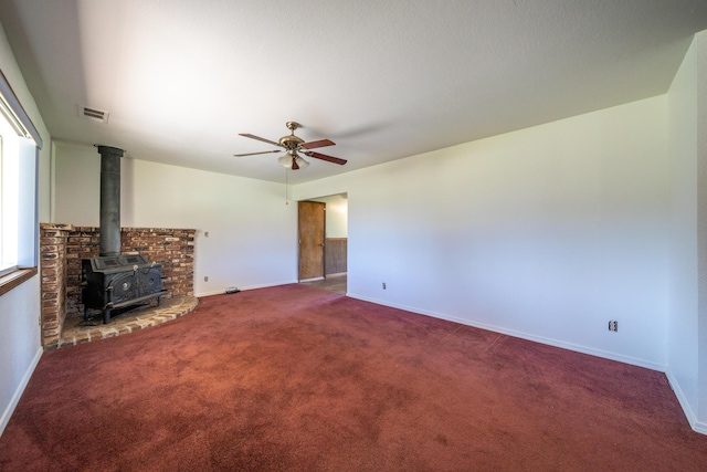 1200 Lema Rd, Redding, CA 96003 - unfurnished living room featuring visible vents, a ceiling fan, carpet flooring, baseboards, and a wood stove