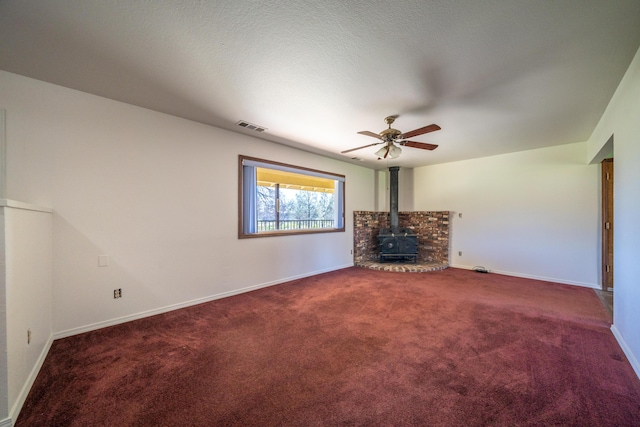1200 Lema Rd, Redding, CA 96003 - unfurnished living room featuring a ceiling fan, visible vents, baseboards, a wood stove, and carpet flooring