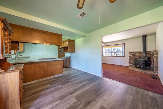 1200 Lema Rd, Redding, CA 96003 - kitchen featuring visible vents, open floor plan, a peninsula, ceiling fan, and a wood stove