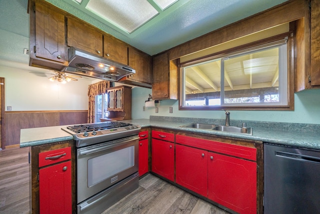 1200 Lema Rd, Redding, CA 96003 - kitchen with stainless steel range with gas cooktop, under cabinet range hood, dishwasher, red cabinets, and a sink