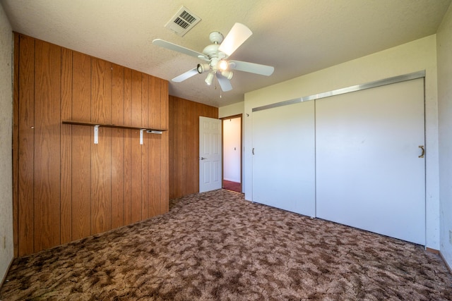 1200 Lema Rd, Redding, CA 96003 - unfurnished bedroom with wooden walls, a ceiling fan, carpet, visible vents, and a closet