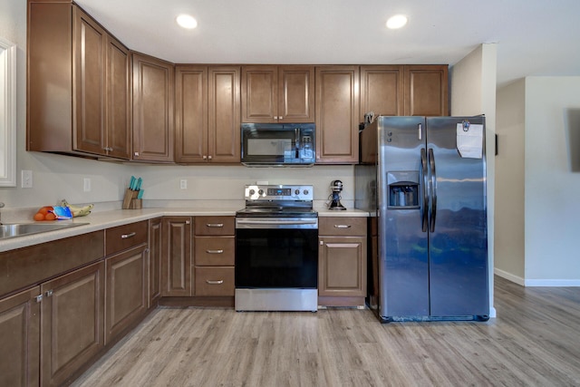 kitchen with light wood finished floors, recessed lighting, stainless steel appliances, light countertops, and baseboards