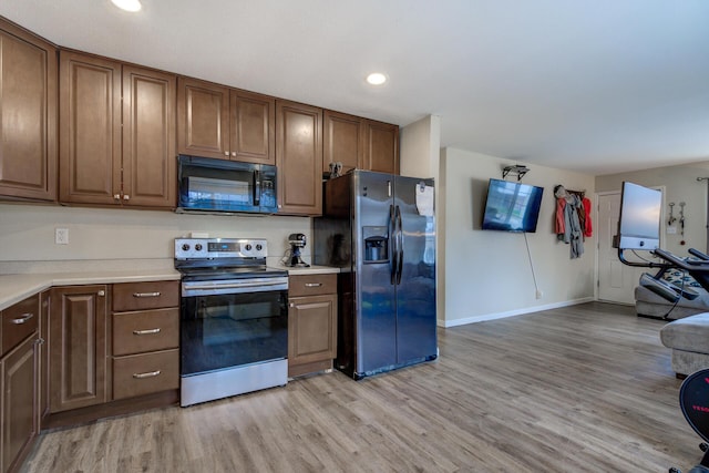 kitchen featuring baseboards, light countertops, recessed lighting, light wood-style floors, and stainless steel appliances