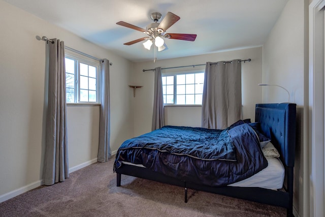 carpeted bedroom featuring multiple windows, a ceiling fan, and baseboards