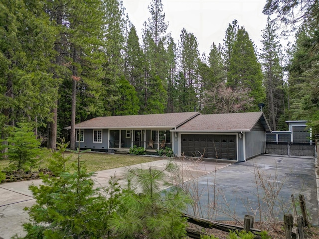 ranch-style house with concrete driveway, an attached garage, a gate, a front lawn, and a porch