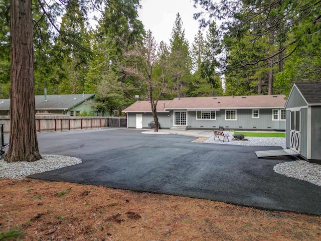 rear view of property with an outbuilding, fence, an outdoor fire pit, a patio area, and a storage shed