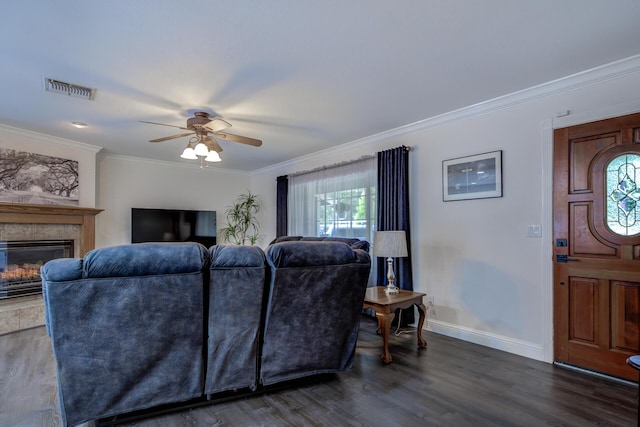 living room with visible vents, crown molding, a ceiling fan, dark wood-type flooring, and a glass covered fireplace