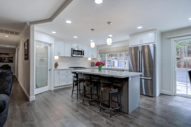 kitchen featuring visible vents, stainless steel appliances, tasteful backsplash, white cabinetry, and a kitchen breakfast bar