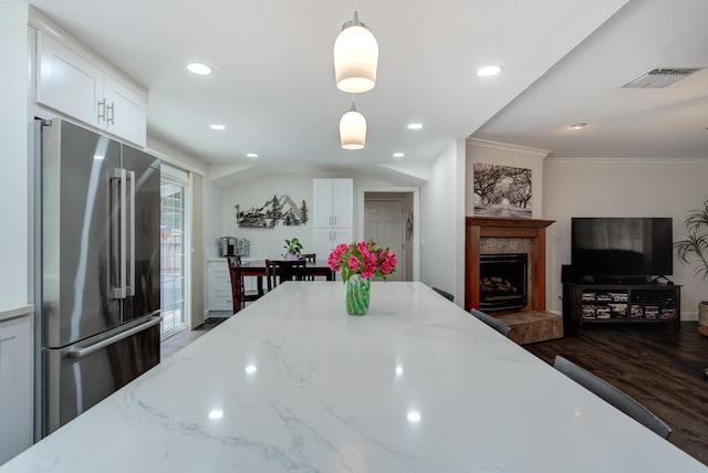 kitchen featuring pendant lighting, high end fridge, white cabinetry, wood finished floors, and visible vents
