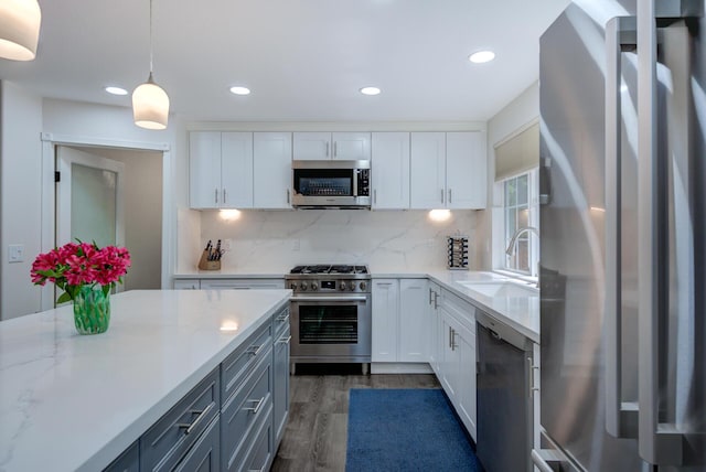 kitchen with dark wood-style flooring, stainless steel appliances, tasteful backsplash, a sink, and pendant lighting