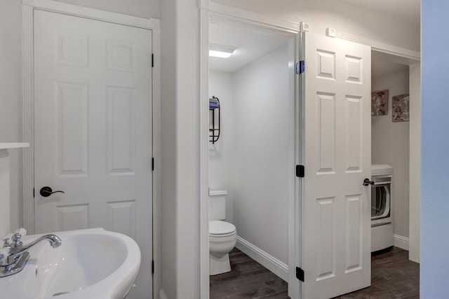 bathroom with toilet, a sink, washer / clothes dryer, and wood finished floors