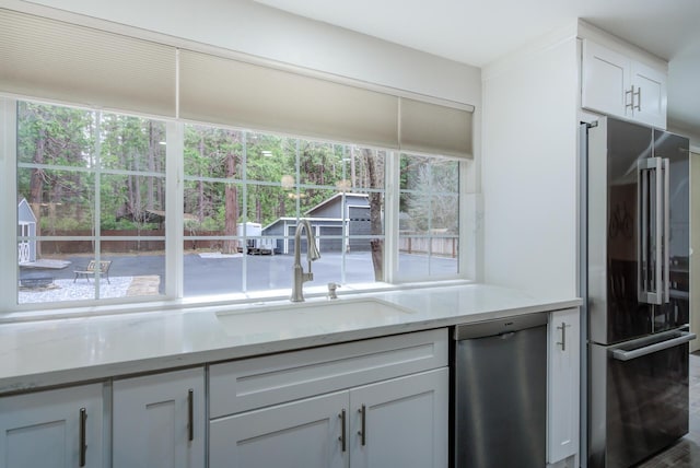 kitchen featuring white cabinets, light stone countertops, a sink, and stainless steel appliances