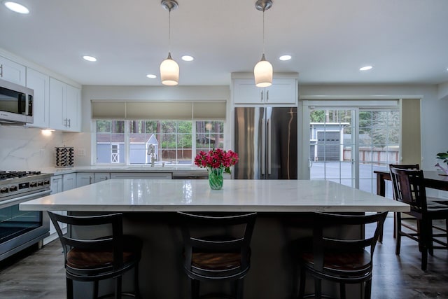 kitchen with backsplash, appliances with stainless steel finishes, light stone counters, and dark wood finished floors