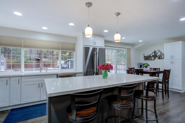 kitchen with white cabinets, light countertops, stainless steel appliances, and a breakfast bar