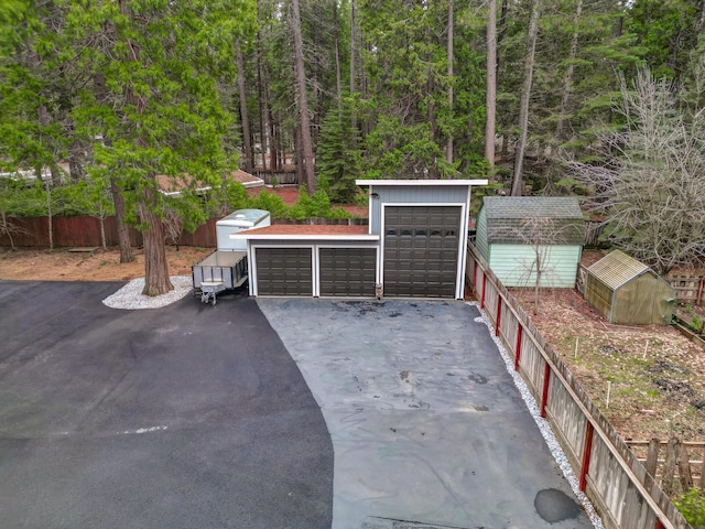 detached garage featuring a wooded view and fence