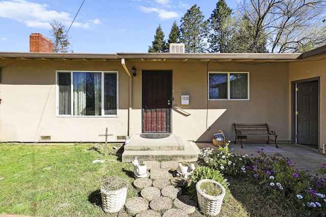 3235 Sharon Ave, Anderson, CA 96007 - property entrance with stucco siding, a chimney, a yard, and a patio area