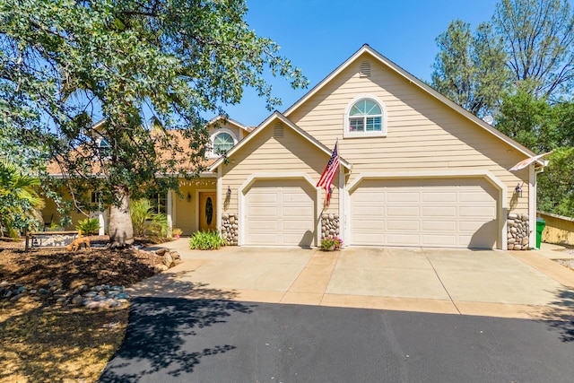 traditional home with driveway, stone siding, and a garage