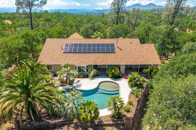 outdoor pool featuring fence private yard, a mountain view, a view of trees, and a patio
