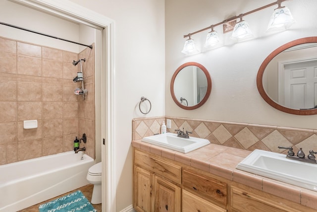 bathroom with double vanity, toilet, bathtub / shower combination, and a sink