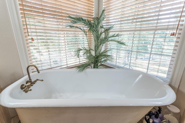 bathroom with a textured wall and a freestanding tub