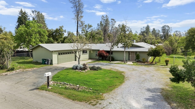 view of front facade featuring a front lawn, fence, a garage, and curved driveway