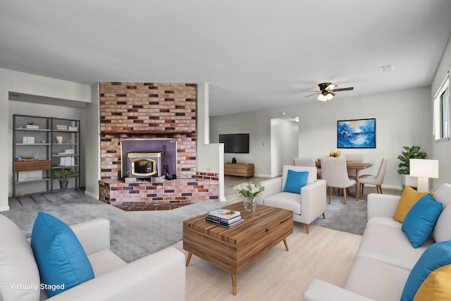 living room with baseboards, visible vents, a ceiling fan, and wood finished floors