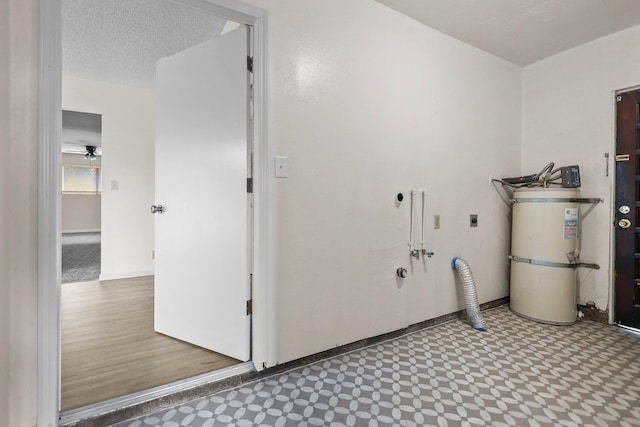 washroom with a textured ceiling, hookup for an electric dryer, secured water heater, laundry area, and baseboards