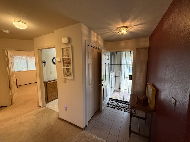 entrance foyer with a textured wall, baseboards, light colored carpet, and a textured ceiling
