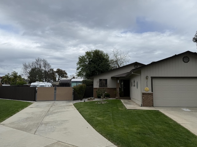 view of front of property featuring driveway, a gate, a front lawn, brick siding, and a garage
