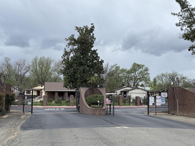 view of street featuring a gate, a gated entry, and curbs