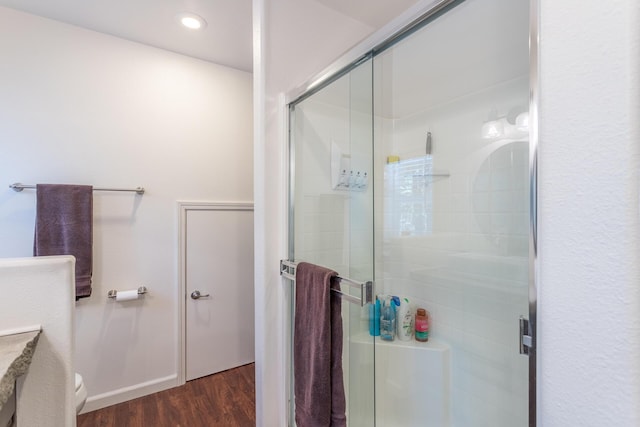 full bath with a stall shower, toilet, wood finished floors, and recessed lighting
