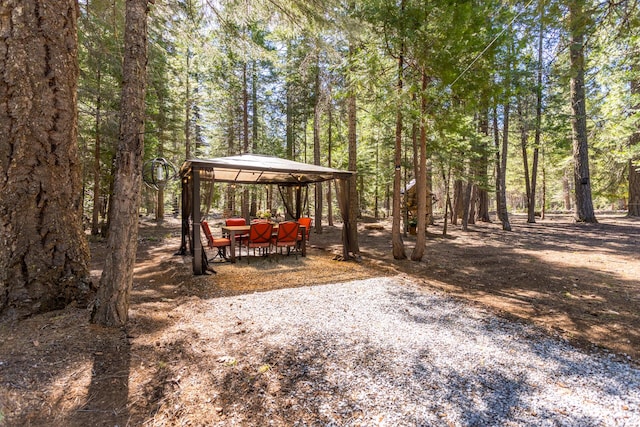 view of yard with a gazebo and a view of trees