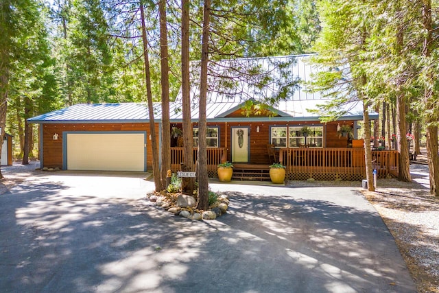 view of front of property featuring covered porch, concrete driveway, a garage, and metal roof