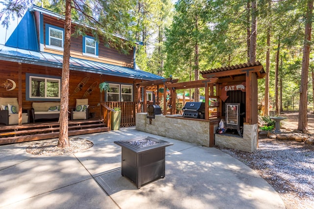 exterior space featuring metal roof, an outdoor fire pit, an outdoor kitchen, and a patio area