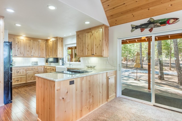 kitchen featuring a sink, tasteful backsplash, light brown cabinetry, and a peninsula