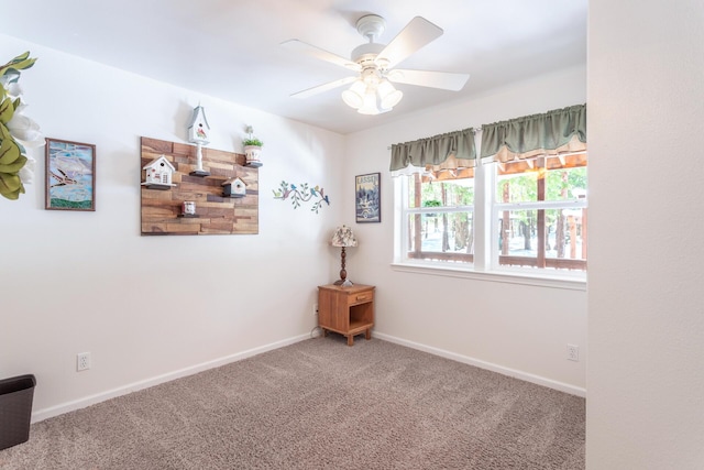 carpeted empty room featuring baseboards and a ceiling fan