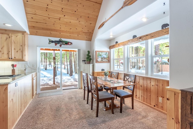 dining space featuring lofted ceiling, wood walls, wood ceiling, and light colored carpet