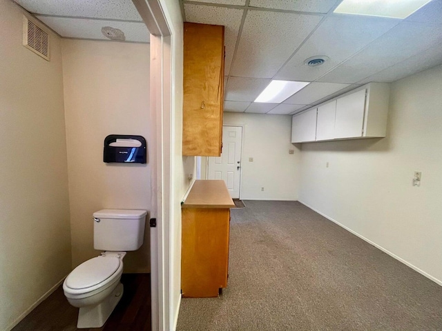bathroom with baseboards, visible vents, toilet, and a drop ceiling