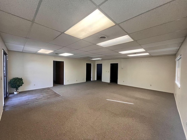 carpeted empty room featuring baseboards, visible vents, and a paneled ceiling