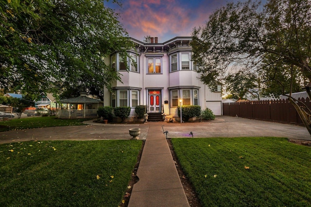 view of front of house with stucco siding, a garage, fence, and a front yard