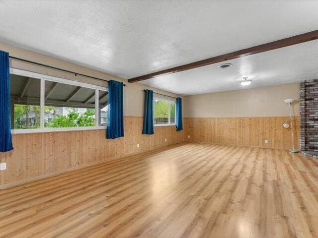 926 Cortina Dr, Orland, CA 95963 - empty room featuring a wainscoted wall, beam ceiling, wooden walls, wood finished floors, and a textured ceiling