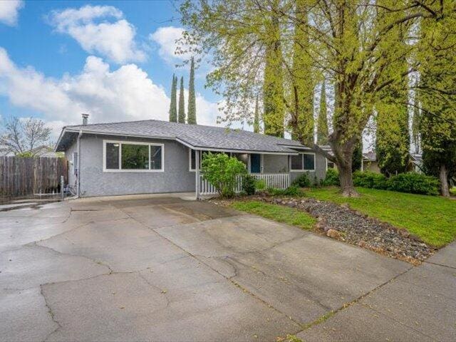 926 Cortina Dr, Orland, CA 95963 - ranch-style house with concrete driveway, stucco siding, fence, a front lawn, and a porch