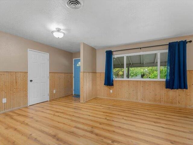 926 Cortina Dr, Orland, CA 95963 - spare room with a wainscoted wall, a textured ceiling, wood walls, visible vents, and wood finished floors