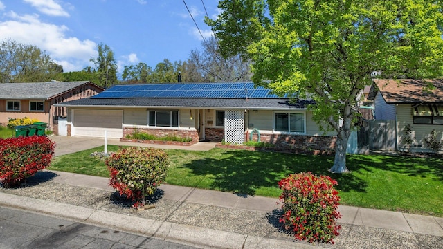ranch-style house featuring roof mounted solar panels, a garage, brick siding, a front lawn, and driveway